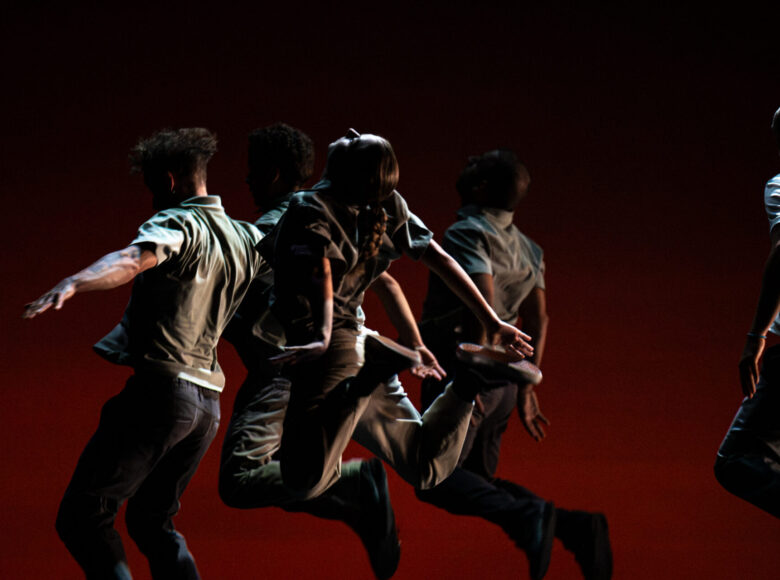 Spektakl teatru tańca. Na scenie grupa osób w dynamicznym układzie tanecznym.