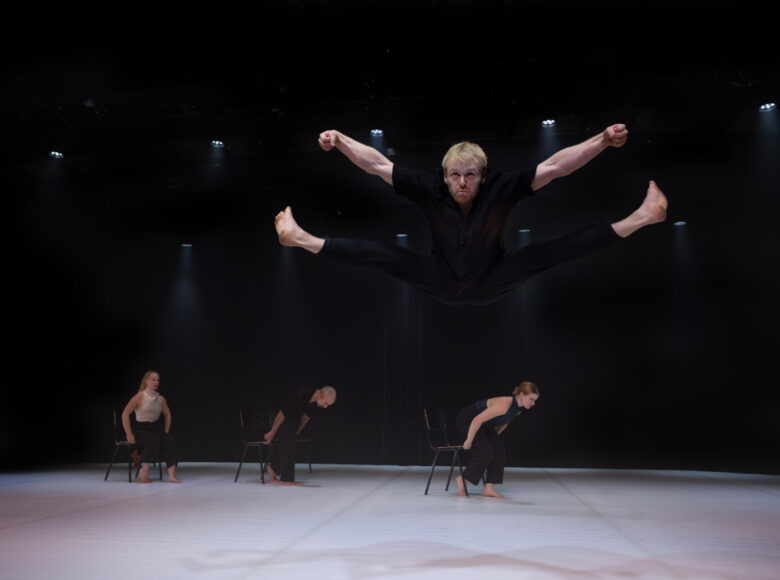 Na scenie grupa tancerek i tancerzy tańca współczesnego w układzie choreograficznym.