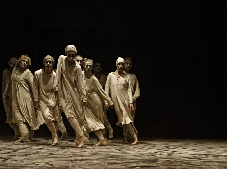 Spektakl teatru tańca. Na scenie grupa osób w dynamicznym układzie tanecznym.
