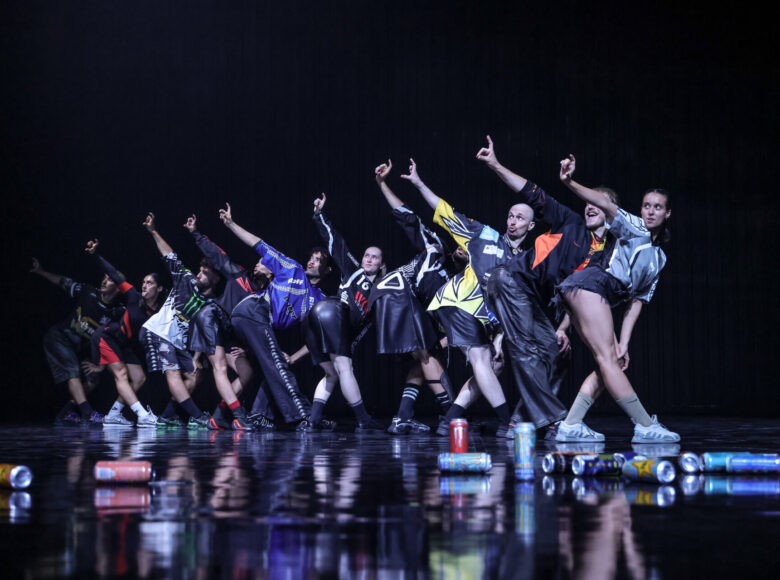 Spektakl teatru tańca. Na scenie grupa osób w dynamicznym układzie tanecznym.