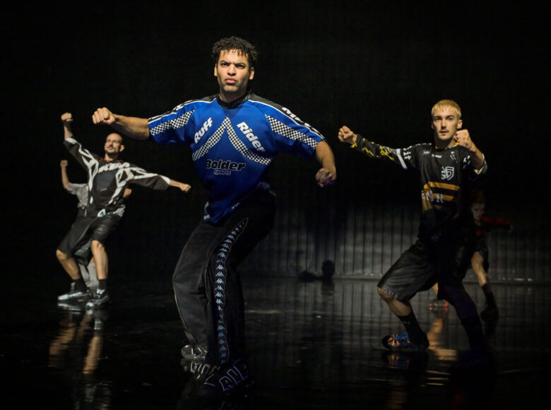 Spektakl teatru tańca. Na scenie trzech tancerzy w dynamicznym układzie tanecznym.