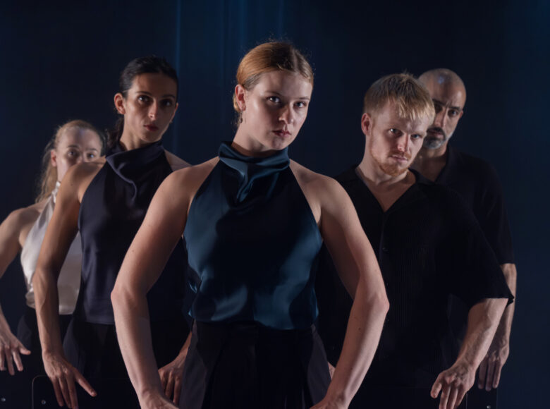 Na scenie grupa tancerek i tancerzy tańca współczesnego w układzie choreograficznym.